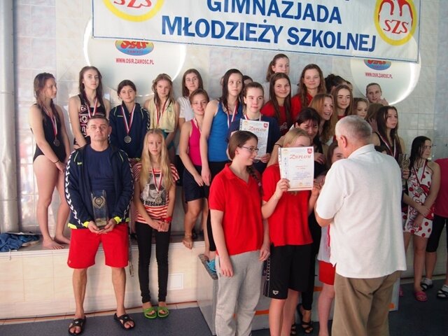 Zdjęcie przedstawia moment wręczania nagród i medali uczennicom biorącym udział w zawodach w pływaniu.