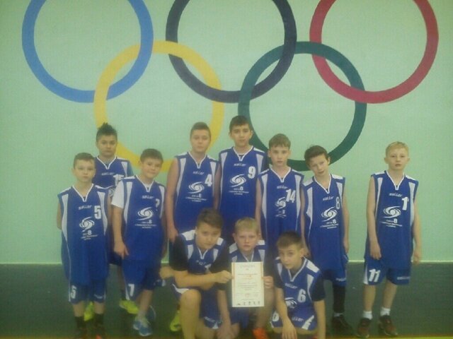 Zdjęcie przedstawia drużynę koszykarską prezentującą dyplom. Chłopcy ubrani są w niebieskie koszykarskie stroje. 