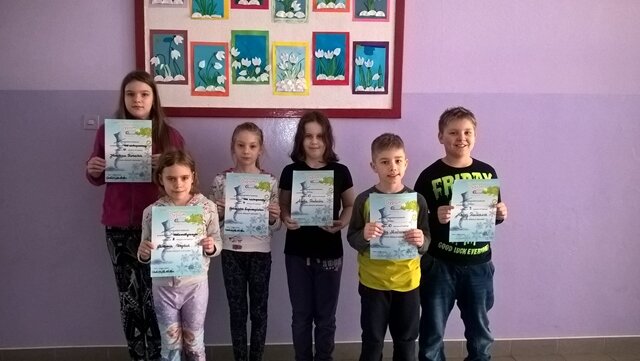 Zdjęcie przedstawia grupę uczniów podczas podsumowania konkursu przedmiotowego “Leon”. Laureaci prezentują otrzymane dyplomy.