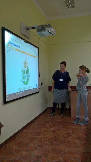 Zdjęcie przedstawiające uczennicę i nauczycielkę przy tablicy interaktywnej podczas zajęć.