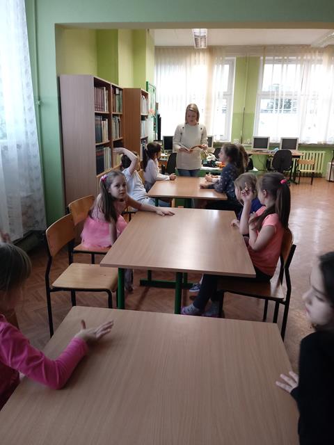 Dzieci słuchają opowieści czytanej przez nauczyciela.