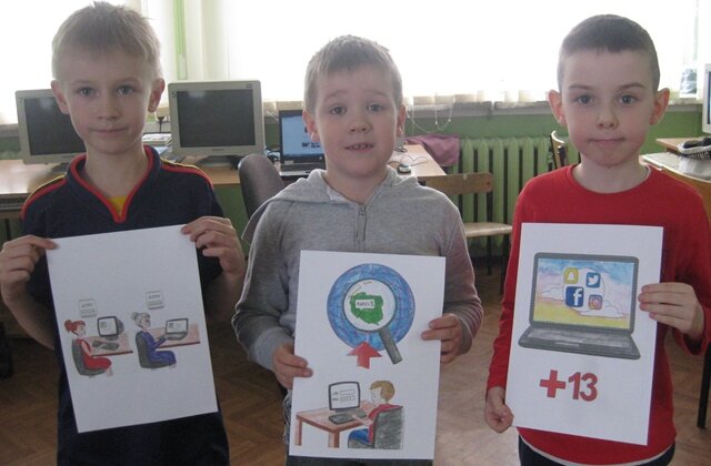 Dzieci trzymają rysunki, które prezentują zasady bezpiecznego korzystania z Internetu.