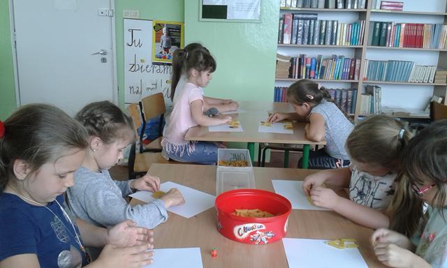 Uczennice podczas zajęć w bibliotece szkolnej. Dziewczynki wykonują prace plastyczne, których głównym materiałem jest makaron.