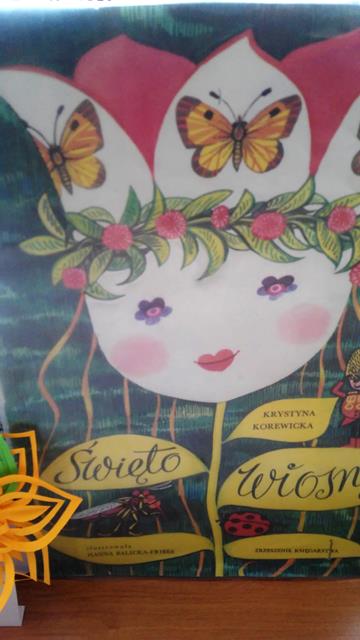 Plakat przedstawia panią wiosnę w formie kwiatka z dziecięcą twarzą. Na listkach łodygi jest zamieszczony napis Święto Wiosny.