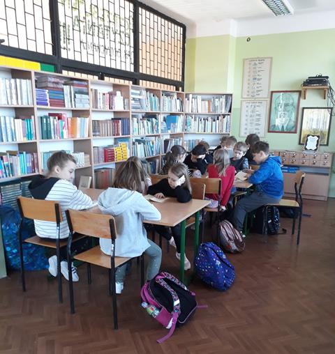 Dzieci biorące udział w cyklicznej akcji „Dzisiaj wszyscy czytamy” przeprowadzonej w bibliotece szkolnej.