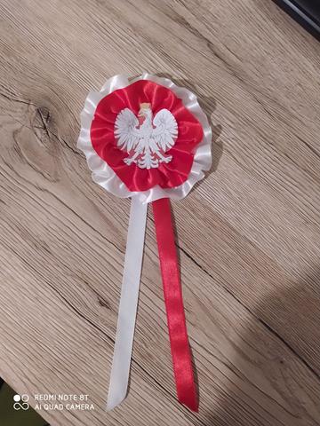 Kotylion w barwach biało - czerwonych z wyeksponowanym orłem w koronie.