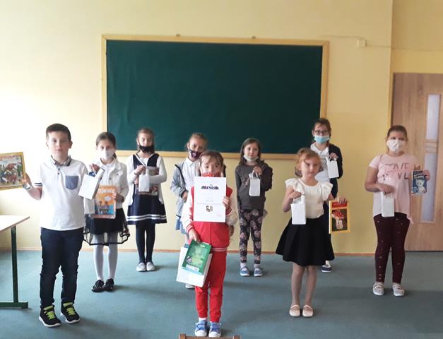 Grupa uczniów wyróżnionych i nagrodzonych w konkursie. Dzieci trzymają w rękach dyplomy i nagrody książkowe.