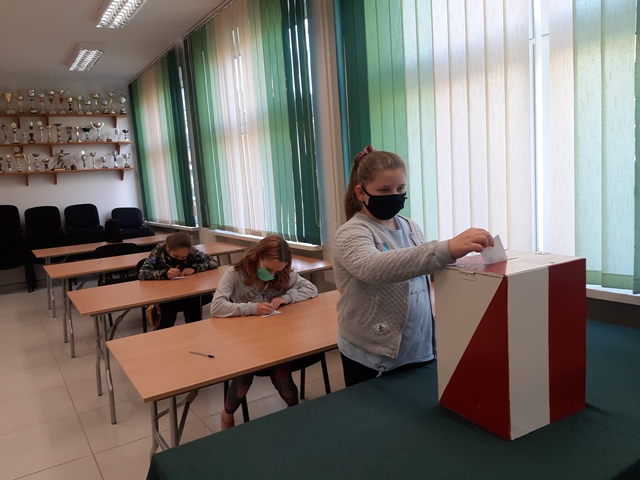 Fotografia przedstawiająca trzy dziewczynki biorące udział w głosowaniu na przedstawicieli Samorządu Uczniowskiego.