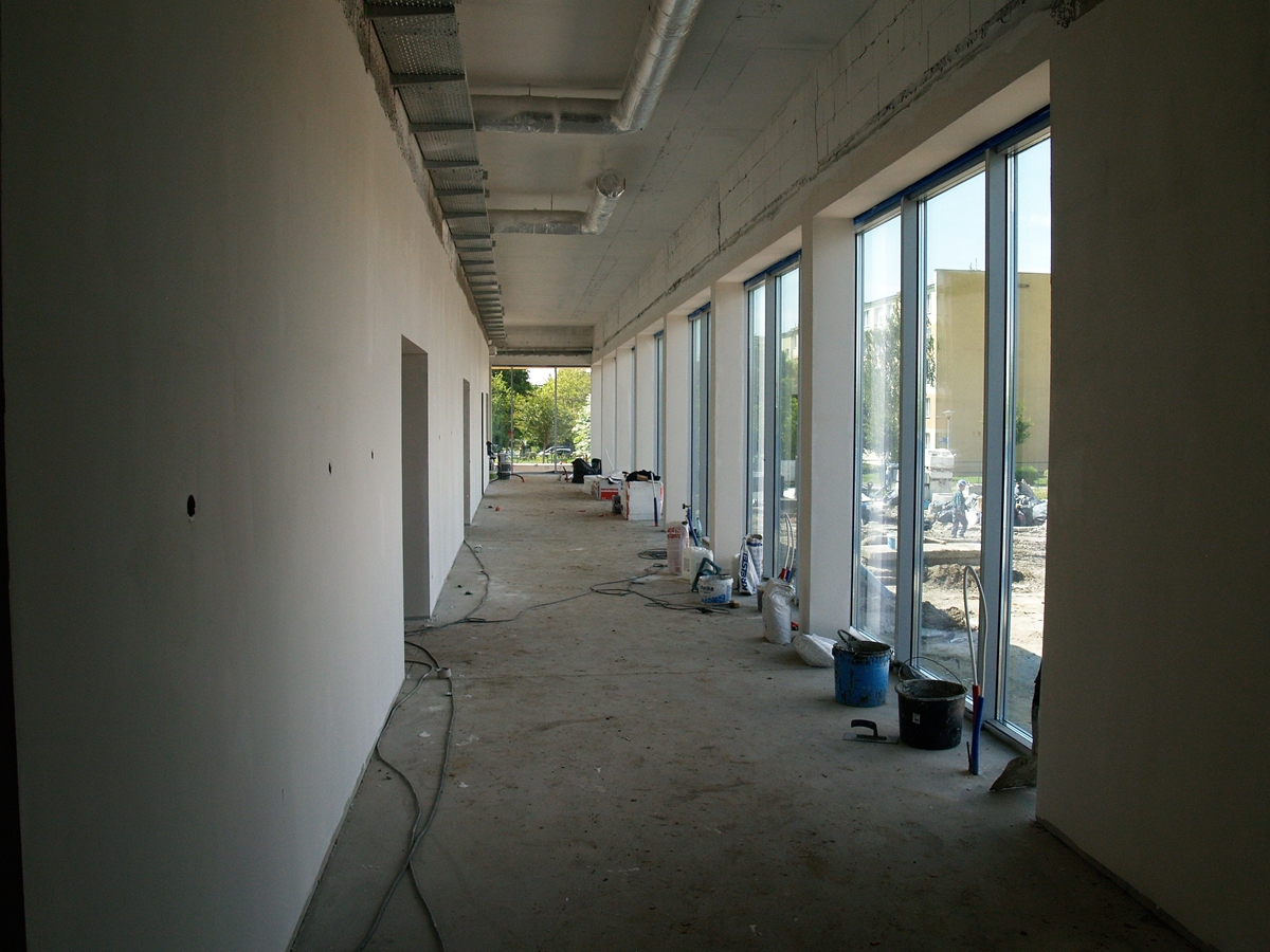 Zdjęcie przedstawia wnętrze budynku basenu - długi korytarz z wykończonymi elementami futryn okiennych.