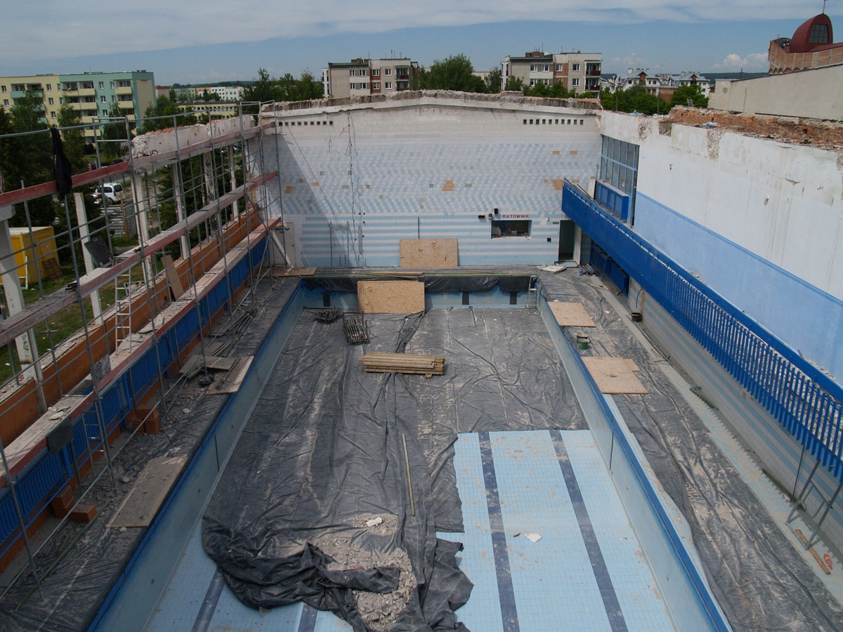 Zdjęcie przedstawiające wnętrze hali basenu podczas początkowej fazy budowy - widok z góry.