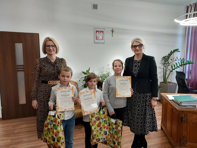 Zdjęcie przedstawia trzech zwycięzców konkursu prezentujących swoje dyplomy i nagrody. Obok dzieci stoją panie dyrektor.