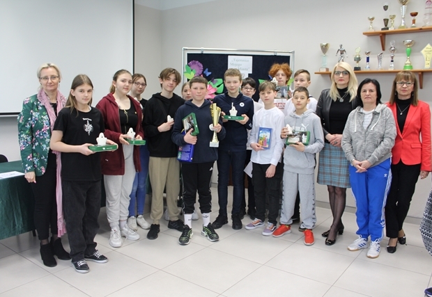 Grupa uczniów i nauczycieli  podczas podsumowania konkursu „O Chełmie wiedzą wszystko”. Uczniowie prezentują nagrody.