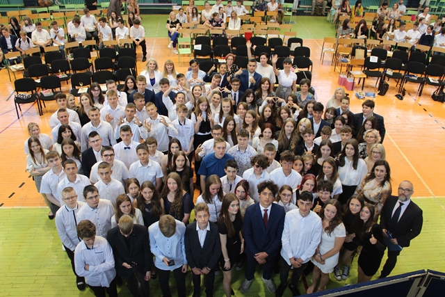 Zdjęcie zrobione z góry i przedstawiające dużą grupę uczniów i nauczycieli  podczas uroczystości zakończenia roku szkolnego.